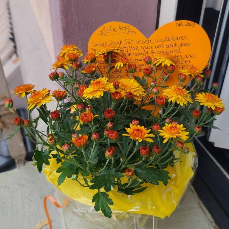 Kundengeschenk als Dank für die Fotos Topf mit leuchtend orange-gelben Chrysanthemen und einer herzförmigen Karte - Geschenk einer Kundin.